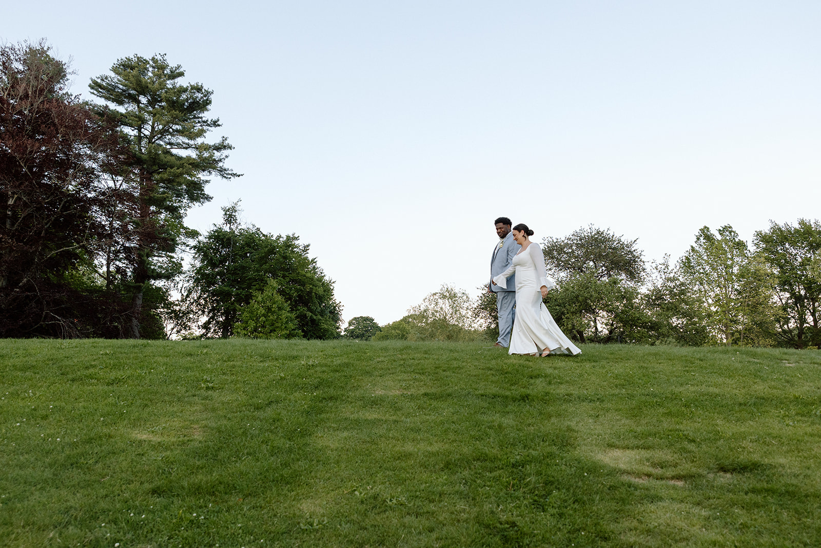 bride and groom walk across hill at their wedding